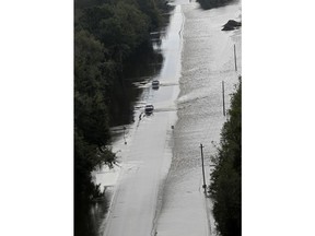 FILE- In this Monday, Sept. 17, 2018, file photo, cars make their way down a road overtopped by rushing floodwater from Hurricane Florence in Dillon, S.C. Navigation apps like Waze are trying to help motorists avoid hurricane flooding, but local authorities say people shouldn't rely on them.