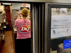 FILE - In this Sunday, Aug. 19, 2018, file photo a woman prepares a cup of ice cream behind a "Help Wanted" sign at a Dairy Queen fast food restaurant in Rutherford, N.J. On Tuesday, Sept. 11, the Labor Department reports on job openings and labor turnover for July.