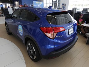 FILE- In this Aug. 30, 2018, photo, buyers sit in a cubicle near a 2018 HR-V on the floor of a Honda dealership in Highlands Ranch, Colo. On Tuesday, Sept. 25, the Conference Board releases its September index on U.S. consumer confidence.