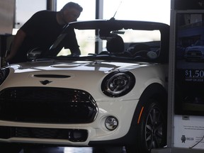 In this Thursday, Aug. 30, 2018, photo, a prospective buyer looks over a 2019 Cooper S convertible on the showroom floor of a Mini dealership in Highlands Ranch, Colo. On Friday, Sept. 14, the Commerce Department releases U.S. retail sales data for August.