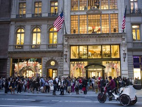 FILE- In this Sept. 8, 2011, file photo shoppers gather outside the Henri Bendel store on Fifth Avenue during Fashion's Night Out in New York. Henri Bendel, known for its brown and white striped shopping bags, is closing in the new year. The luxury retailer's parent company, L Brands Inc., said that Henri Bendel's 23 stores and its website will shut down in January but that it'll carry new merchandise during the holiday season.
