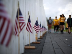FILE- In this May 31, 2018 file photo, visitors to the Flight 93 National Memorial pause at the Wall of Names containing the names of the 40 passengers and crew of United Flight 93 that were killed in this field in Shanksville, Pa. on Sept. 11, 2001. Officials on Sunday, Sept. 9 will dedicate the Tower of Voices, a 93-foot-high concrete and steel structure that features a wind chime for each of the 40 passengers and crew who died when the aircraft crashed into the rural western Pennsylvania field.