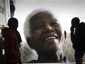 FILE - In this June 27, 2013 file photo, large photographs of former South African President Nelson Mandela are displayed at the Nelson Mandela Legacy Exhibition at the Civic Centre in Cape Town, South Africa. The United Nations is seeking to harness the soaring symbolism of Mandela, whose South African journey from anti-apartheid leader to prisoner to president to global statesman is one of the 20th century's great stories of struggle, sacrifice and reconciliation. The unveiling of a statue of Mandela, born 100 years ago, with arms outstretched at the U.N. building in New York on Monday, Sept. 24, 2018, opens a peace summit at the General Assembly.