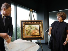 United States Attorney Geoffrey Berman, left, unveils a Renoir painting with Sylvie Sulitzer at a news conference, Wednesday, Sept. 12, 2018, in New York. The 1919 oil painting "Femmes Dans Un Jardin" was seized in Paris by the Nazis from Sulitzer's grandfather. It was returned to Sulitzer, a delicatessen owner from the south of France, in the ceremony.