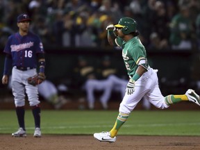 Oakland Athletics' Khris Davis, right, celebrates as he passes Minnesota Twins' Ehire Adrianza (16) after hitting a two-run home run off Jose Berrios during the first inning of a baseball game Friday, Sept. 21, 2018, in Oakland, Calif.