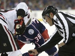 Linesman Matt MacPherson, right, prepares to drop the puck for a faceoff during the second period of a preseason NHL hockey game between the Columbus Blue Jackets and the Chicago Blackhawks Tuesday, Sept. 18, 2018, in Columbus, Ohio. A point of emphasis at last week's training camp for NHL officials was faceoffs, after linesmen spent much of last season cracking down on players attempting to gain an advantage by creeping in from the hash mark or dropping to their knees for leverage. Numerous videos featured miked-up linesmen being assertive by warning players to make sure their feet and sticks were set while lining up inside the circle.