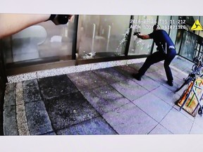 FILE - In this Sept. 7, 2018, file photo, suspect Omar Enrique Santa Perez lies on the ground, seen behind glass of left window pane, after being engaged by police as seen on police body camera video displayed during a news conference detailing the shooting incident of the previous day in the downtown business district in Cincinnati.  Whitney Austin survived some 12 gunshots during the Sept. 6 shooting.  She recounted her ordeal in a taped interview that aired Wednesday, Sept. 26 on ABC-TV's "Good Morning America."