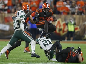 Cleveland Browns running back Carlos Hyde (34) jumps over defenders during the second half of an NFL football game against the New York Jets, Thursday, Sept. 20, 2018, in Cleveland.