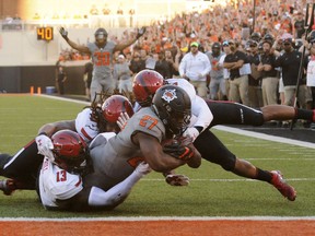 Oklahoma State running back J.D. King (27) scores a touchdown while being tackled by Texas Tech linebackers Kolin Hill, left, and Dakota Allen, back center, and defensive back John Bonney during the first half of an NCAA college football game in Stillwater, Okla., Saturday, Sept. 22, 2018.