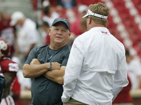 UCLA head coach Chip Kelly, left, talks with Oklahoma defensive coordinator Mike Stoops, right, before their NCAA college football game in Norman, Okla., Saturday, Sept. 8, 2018.