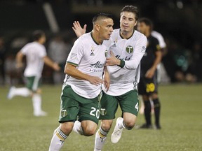 Portland Timbers' David Guzman (20) celebrates his first-half goal against the Columbus Crew during a Major League Soccer match Wednesday, Sept. 19, 2018, in Portland, Ore. At right is Portland's Jorge Villafana.