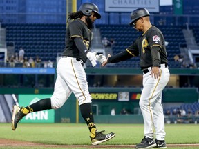Pittsburgh Pirates' Josh Bell, left, is greeted by third base coach Joey Cora as he rounds the bases after hitting a solo home run against the Milwaukee Brewers in the first inning of a baseball game, Friday, Sept. 21, 2018, in Pittsburgh.