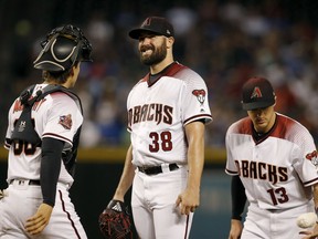 Arizona Diamondbacks starting pitcher Robbie Ray (38) gets a visit from catcher John Ryan Murphy, left, and shortstop Nick Ahmed (13) during the first inning of a baseball game against the Los Angeles Dodgers, Monday, Sept. 24, 2018, in Phoenix.