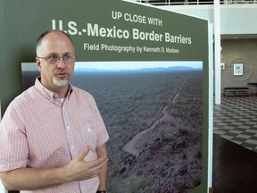 In this Friday, Sept. 14, 2018, photo, Kenneth Madsen, an Ohio State University-Newark geography professor and border wall expert, discusses his photo exhibit of border wall pictures and maps, "Up Close with U.S.-Mexico Border Barriers," in Newark, Ohio. Madsen says the goal of his exhibit, opening Wednesday, Sept. 19  is to raise awareness about an issue that most people have only seen on the news.