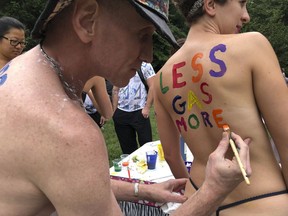 Bicyclist Olivia Neely gets a message advocating for less consumption of fossil fuels painted on her back at the Philly Naked Bike Ride in Philadelphia, Saturday, Sept. 8, 2018.