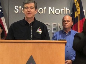 In this Sept. 12, 2018 photo, North Carolina Gov. Roy Cooper, left, speaks at a news conference about Hurricane Florence preparedness as attended by state Transportation Secretary Jim Trogdon, right, listens in Raleigh, N.C. Cooper has been praised by many, including Republicans, for his handling of the state's immediate response to Florence