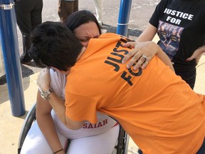 Gina Torres, seated, gets a hug from Bridgette Perkins during a rally in St. Louis Thursday, Sept. 20, 2018, demanding that a police internal investigations unit complete its probe into the fatal police shooting of Torres' son, Isaiah Hammett. Hammett was killed in a SWAT raid at his home in June 2017. Perkins' son, Isiah Perkins, also was killed by a St. Louis officer, in July 2017.