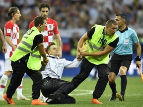 In this July 15, 2018, stewards pull Pyotr Verzilov, a member of the feminist protest group Pussy Riot off the pitch after he stormed onto the field and interrupted the final match between France and Croatia at the 2018 soccer World Cup in the Luzhniki Stadium in Moscow, Russia.