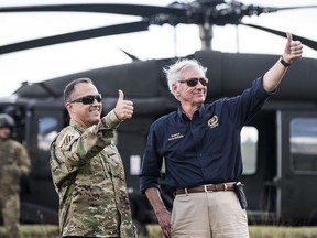 South Carolina Gov. Henry McMaster, right, and National Guard Lt. Col. Jay McElveen give thumbs-up to rescue workers after Hurricane Florence struck the Carolinas, Monday, Sept. 17, 2018, near Wallace, S.C. A fire rescue team saved two people stuck on the roof of a vehicle in floodwaters caused by the storm.