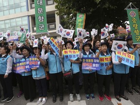 South Koreans wave their national flags during a rally to wish for the successful inter-Korean summit near the presidential Blue House in Seoul, Tuesday, Sept. 18, 2018. South Korean President Moon Jae-in said Monday that he will push for "irreversible, permanent peace," and for better dialogue between Pyongyang and Washington, during "heart-to-heart" talks with North Korean leader Kim Jong Un this week. The signs read: " Denuclearization."