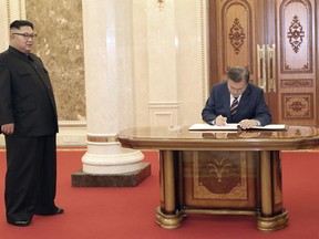 South Korean President Moon Jae-in signs a guestbook as North Korean leader Kim Jong Un looks on before their summit at the headquarters of the Central Committee of the Workers' Party in Pyongyang, North Korea, Tuesday, Sept. 18, 2018. (Pyongyang Press Corps Pool via AP)