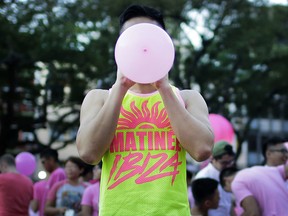 In this July 1, 2017, file photo, a participant blows a pink balloon at a park where thousands gathered for the annual Pink Dot gay pride event in Singapore.