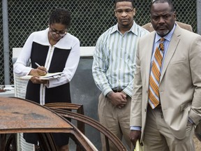 FILE - In this Oct. 12, 2017 photograph, Quinton Tellis, center, stands with his defense attorneys Darla Palmer, left, and Alton Peterson, right, near the remains of Jessica Chambers car in Batesville, Miss. Tellis was charged with burning 19-year-old Jessica Chambers to death. The trial ended in a mistrial, but Tells is to be retried in Chambers' burning death, starting Tuesday, Sept. 25.