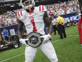 In this Sept. 1, 2018, photo provided by the Mississippi Athletics Department, Mississippi wide receiver A. J. Brown displays the team's "Nasty Wide Outs" belt during an NCAA college football game against Texas Tech in Houston. College football sidelines across the country are featuring everything from wrestling-style robes to boxing gloves as teams try to mimic the success Miami had last season with its turnover chain.