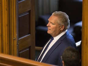 Ontario Premier Doug Ford looks out from a side room as protesters are removed from the public gallery by Queens Park Legislature Security during Question Period at the Ontario Legislature in Toronto on Wednesday September 12, 2018.