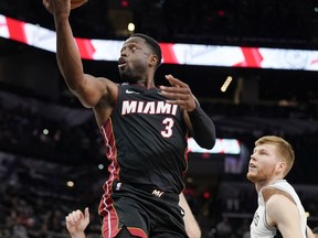 Miami Heat's Dwyane Wade (3) shoots as San Antonio Spurs' Davis Bertans looks on during the first half of an NBA preseason basketball game, Sunday, Sept. 30, 2018, in San Antonio.