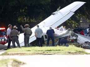 Investigators look at a small plane that crashed just west of Highway 6, Wednesday, Sept. 19, 2018, in Sugar Land, Texas. Authorities say a small plane operated by the Drug Enforcement Administration crashed on the street in suburban Houston, hitting two vehicles and injuring one person.