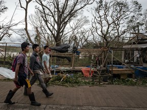 Residents walk past damaged houses on September 15, 2018 in Gattaran, Philippines. Typhoon Mangkhut battered northern Philippines as it made landfall Saturday morning leaving at least five people dead and millions of pesos in damages.