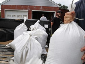 Seth Bazemore IV, center moves sandbags, Tuesday, Sept. 11, 2018, in the Willoughby Spit area of Norfolk, Va., as they make preparations for Hurricane Florence.