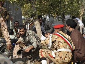In this photo provided by the Iranian Students' News Agency, ISNA, Iranian armed forces members and civilians take shelter in a shooting during a military parade marking the 38th anniversary of Iraq's 1980 invasion of Iran, in the southwestern city of Ahvaz, Iran, Saturday, Sept. 22, 2018. Gunmen attacked the military parade, killing at least eight members of the elite Revolutionary Guard and wounding 20 others, state media said.