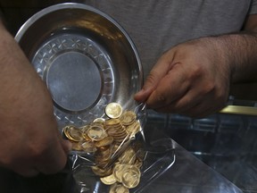 In this Wednesday, Aug. 12, 2018 photo, an Iranian goldsmith counts gold coins in the sprawling Grand Bazaar, that has seen customers eagerly buying gold as a hedge against the falling Iranian rial, in Tehran, Iran. Fear over the economy has brought many to the bazaar in recent days to buy what they can before their savings further dwindle away.