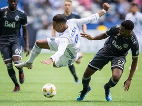 San Jose Earthquakes' Danny Hoesen, left, is upended by Vancouver Whitecaps' Aaron Maund (22) during the first half of an MLS soccer game in Vancouver, on Saturday September 1, 2018.