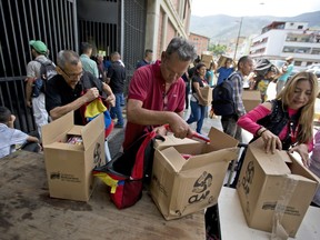 In this July 6, 2018 photo, employees of a government-supported cultural centre collect their boxes with subsided food distributed under government program named "CLAP" in downtown Caracas, Venezuela.