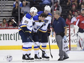 St. Louis Blues center Oskar Sundqvist, second from left, is helped off the ice by right wing Dmitrij Jaskin (23) and defenseman Vince Dunn (29) during the second period of an NHL preseason hockey game after he was checked by Washington Capitals' Tom Wilson, Sunday, Sept. 30, 2018, in Washington.