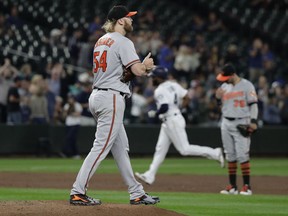 Baltimore Orioles starting pitcher Andrew Cashner, left, stands on the mound after he gave up a solo home run to Seattle Mariners' Denard Span, rounding the bases second from right, during the fifth inning of a baseball game Wednesday, Sept. 5, 2018, in Seattle. The homer was back-to-back with one hit by Mariners' Nelson Cruz.