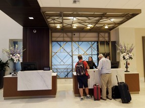 In this Wednesday, Sept. 5, 2018, photo guests stand at the front desk at the Embassy Suites by Hilton hotel in Seattle's Pioneer Square neighborhood in Seattle. Housekeeping workers at the hotel use devices that let them push a button and summon help if they are in a threatening situation while working.