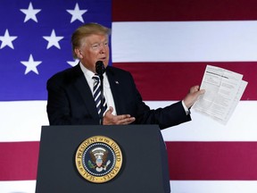 In this Aug. 31, 2018, photo, President Donald Trump holds up a list of his administrations accomplishments while speaking at a Republican fundraiser at the Carmel Country Club in in Charlotte, N.C.