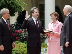 FILE - In this June 1, 2006 file photo, from left to right, President Bush, watches the swearing-in of Brett Kavanaugh as Judge for the U.S. Court of Appeals for the District of Columbia by U.S. Supreme Court Associate Justice Anthony M. Kennedy, far right, during a ceremony in the Rose Garden of the White House, in Washington. Holding the Bible is Kavanaugh's wife Ashley Kavanaugh. Kavanaugh has been a conservative team player, and the Supreme Court nominee has stepped up to make a play at key moments in politics, government and the law dating to the Bill Clinton era.