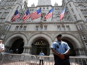 FILE - In this June 30, 2018, file photo, aw enforcement officers stand guard in front of the Trump Hotel in Washington. A federal district judge in Washington says a group of nearly 200 Democratic senators and representatives has legal standing to sue President Donald Trump to prove he violated the U.S. Constitution's emoluments provision.
