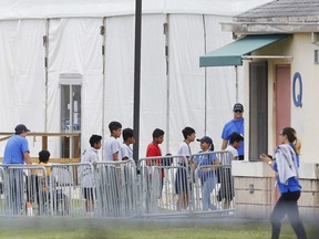 FILE - In this June 20, 2018, file photo, Immigrant children walk in a line outside the Homestead Temporary Shelter for Unaccompanied Children a former Job Corps site that now houses them in Homestead, Fla. A Senate subcommittee has found that federal officials for the second time lost track of nearly 1,500 migrant children earlier this year after a government agency placed the minors in the custody of adult sponsors in communities nationwide.