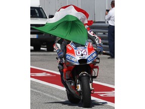 Italy's Andrea Dovizioso is covered by the Italian flag as he arrives at pits after winning the MotoGP race during the San Marino Motorcycle Grand Prix at the Misano circuit in Misano Adriatico, Italy, Sunday, Sept. 9, 2018.