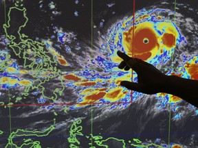 Filipino forecaster Meno Mendoza illustrates the path of Typhoon Mangkhut, locally named "Typhoon Ompong" as it approaches the Philippines with sustained winds of 205 kilometers per hour (127 miles per hour) and gusts of up to 255 kph (158 mph), at the Philippine Atmospheric, Geophysical and Astronomical Services Administration in metropolitan Manila, Philippines on Wednesday, Sept. 12, 2018. Philippine officials say they plan to evacuate thousands of villagers, shut down schools and offices and scramble to harvest rice and corn as the most powerful typhoon so far this year menacingly roars toward the country's north.