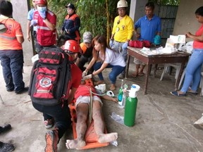 In this handout photo provided by Philippine Red Cross-Cebu Chapter, Red Cross volunteers treat a victim after she was pulled out of her house that was struck by a landslide in Naga city, Cebu province central Philippines on Thursday, Sept. 20, 2018. A Philippine official says several people were killed and more are feared buried in a landslide that hit two villages amid heavy rains in the central Philippines.