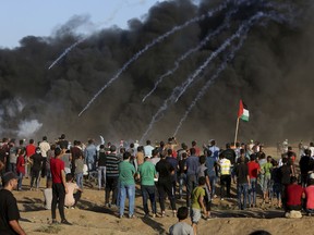 Protesters gather while Israeli troops fired teargas near the fence of Gaza Strip border with Israel during a protest east of Gaza City, Friday, Sept. 21, 2018. Gaza's Health Ministry says a Palestinian was killed and dozens injured by Israeli fire at a border protest.