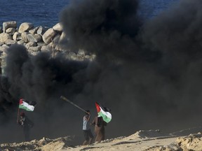 A protester hurls stones at Israeli troops during a protest on the beach at he border with Israel near Beit Lahiya, northern Gaza Strip, Monday, Sept. 17, 2018.