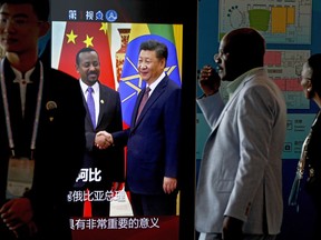 African delegates walk by a screen panel showing a footage of Chinese President Xi Jinping with Ethiopia's Prime Minister Abiy Ahmed ahead of the Forum on China-Africa Cooperation in Beijing, Monday, Sept. 3, 2018. African leaders will likely press their Chinese hosts at a conference this week to help narrow their trade deficits with Beijing by shifting more manufacturing to their continent, the chief executive of the biggest African bank said.